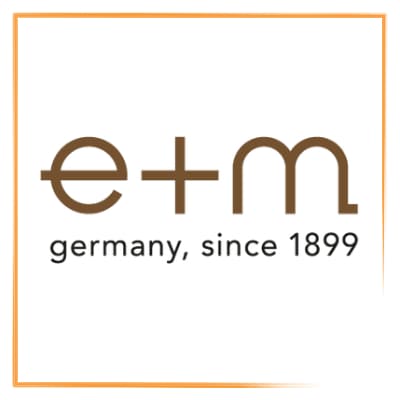 Orange gerahmte Markenkachel mit Logo von e+m. Minimalistischer, schnoerkelloser Schriftzug in Kleinbuchstaben e und m getrennt durch ein Pluszeichen. Direkt darunter in anthrazitfarbenen Kleinbuchstaben  germany, since 1899. 